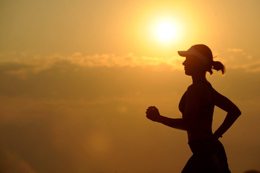 woman running in sunset (fitness goals)