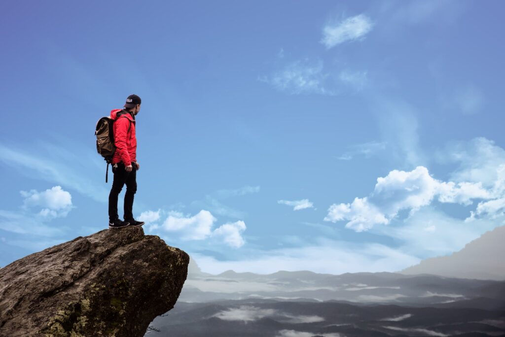 man standing at top of mountain (example of good long-term goals)

