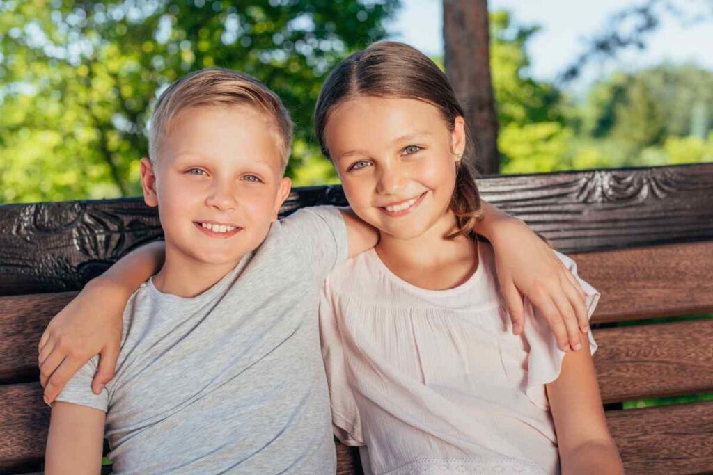 2 kids with complementary outfits on a bench