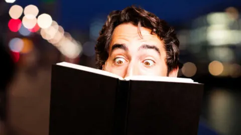 man reading a black book and looking offended
