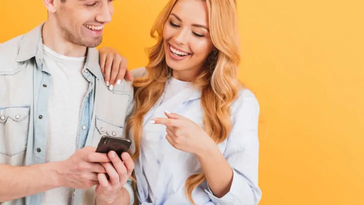 woman laughing after looking at joke on her boyfriend's phone
