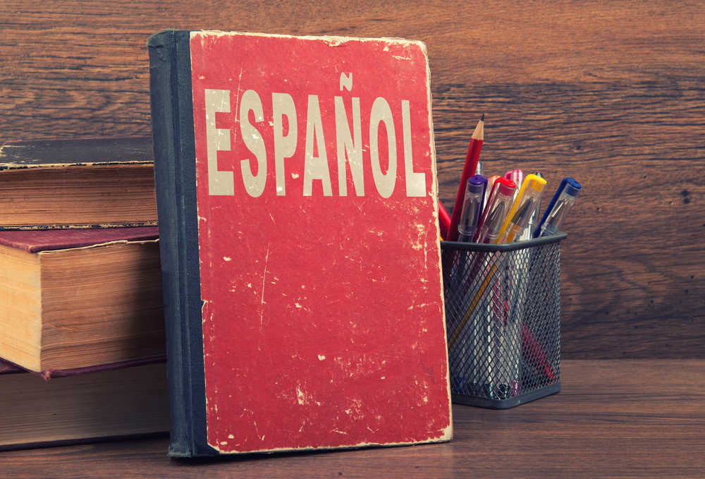 espanol written on a book with a red cover on a wooden table