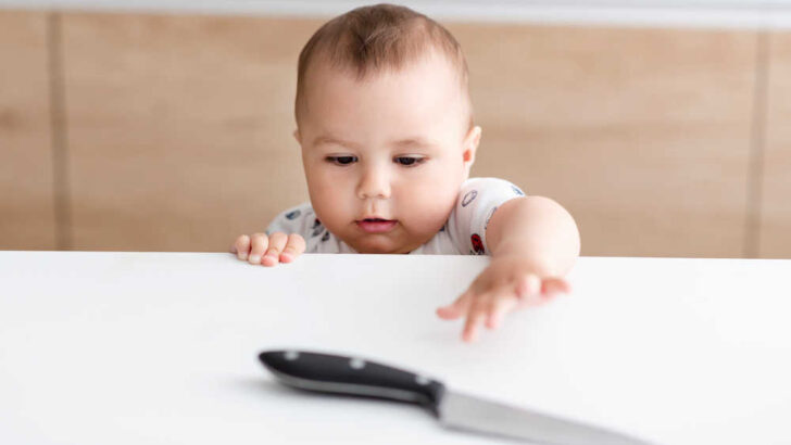 baby taking a risk by reaching over the counter