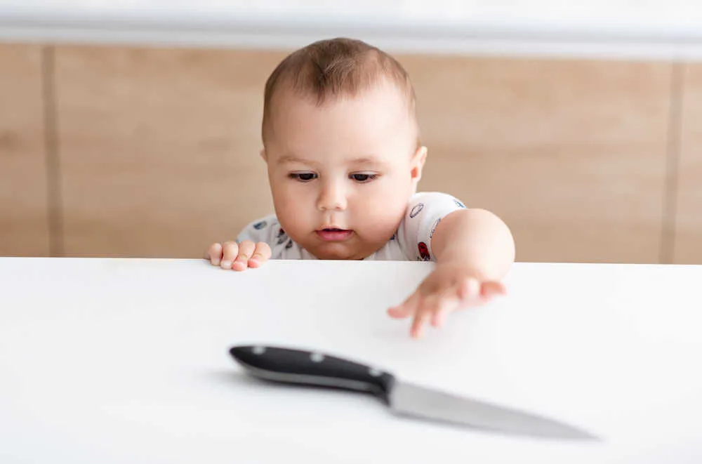 baby taking a risk by reaching over the counter