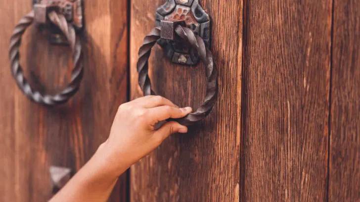 closeup of a hand knocking on a wooden door