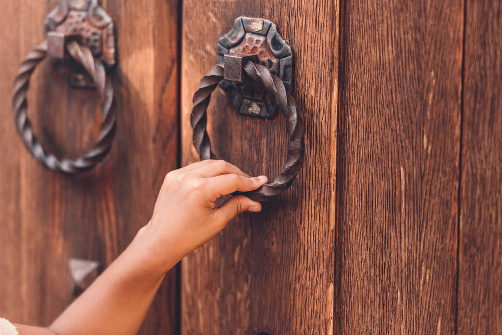 closeup of a hand knocking on a wooden door