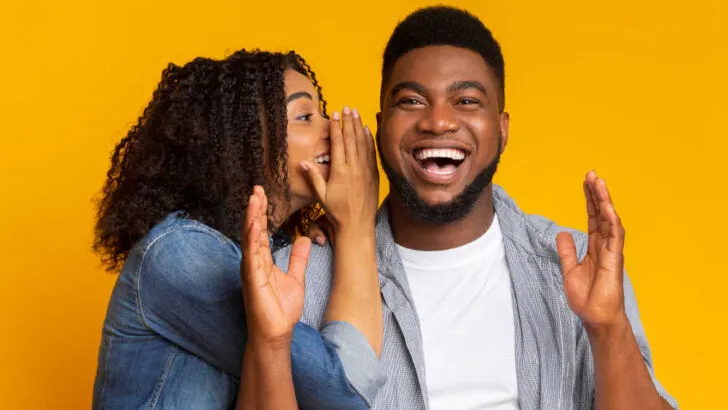 woman whispering a joke to a guy who is laughing