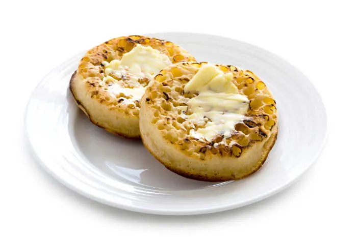 hot toasted crumpets with butter on a white background