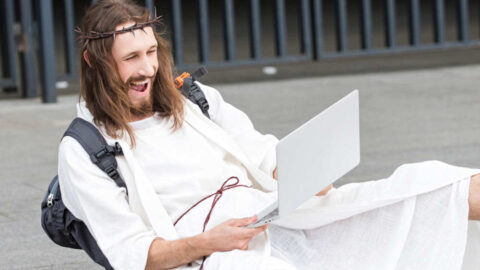 laughing jesus looking at a computer for jokes