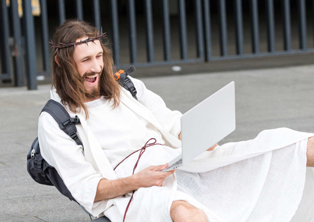 laughing jesus looking at a computer for jokes